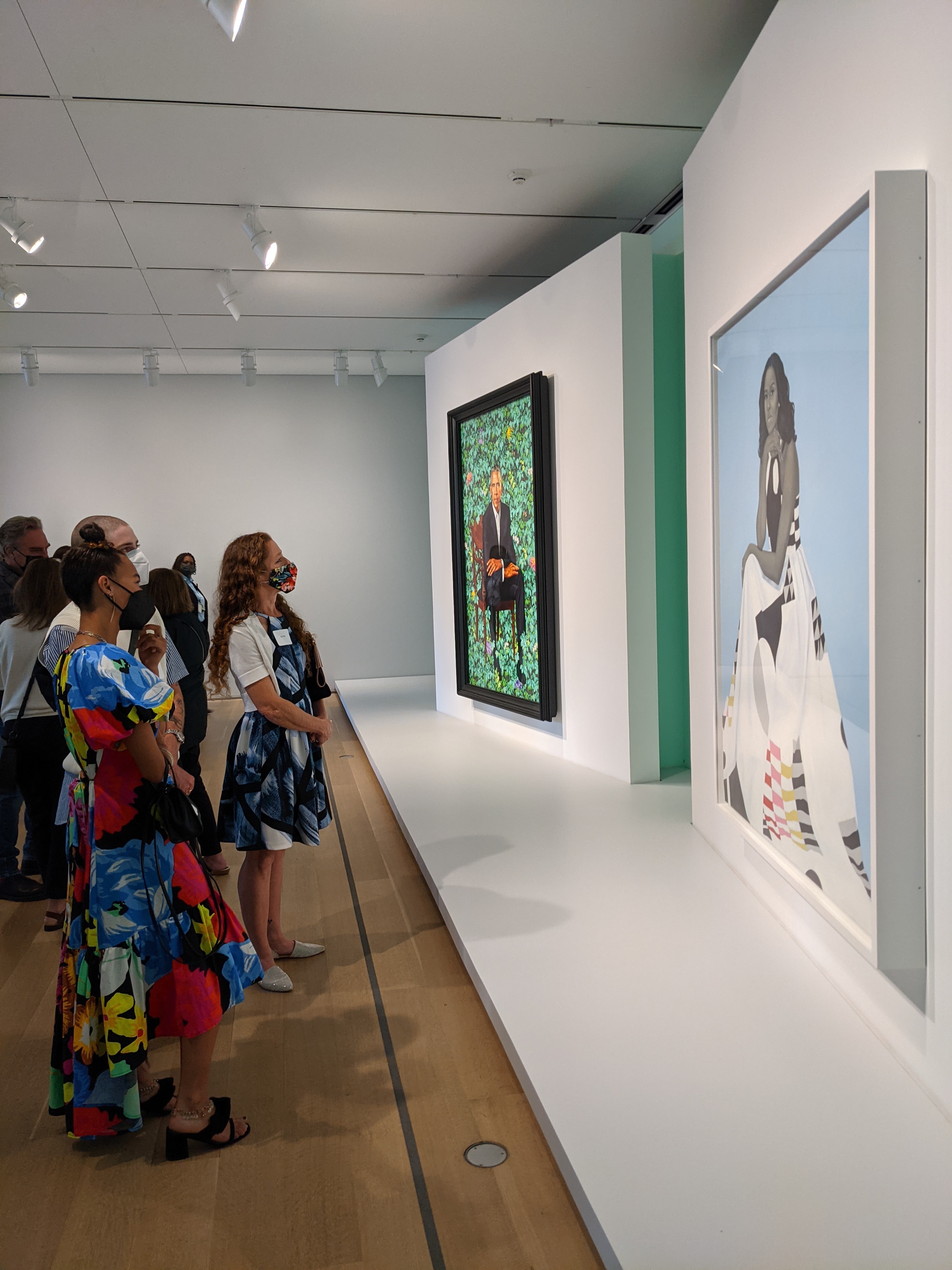 A small group of people view the portraits of former President Barack Obama and First Lady Michelle Obama.
