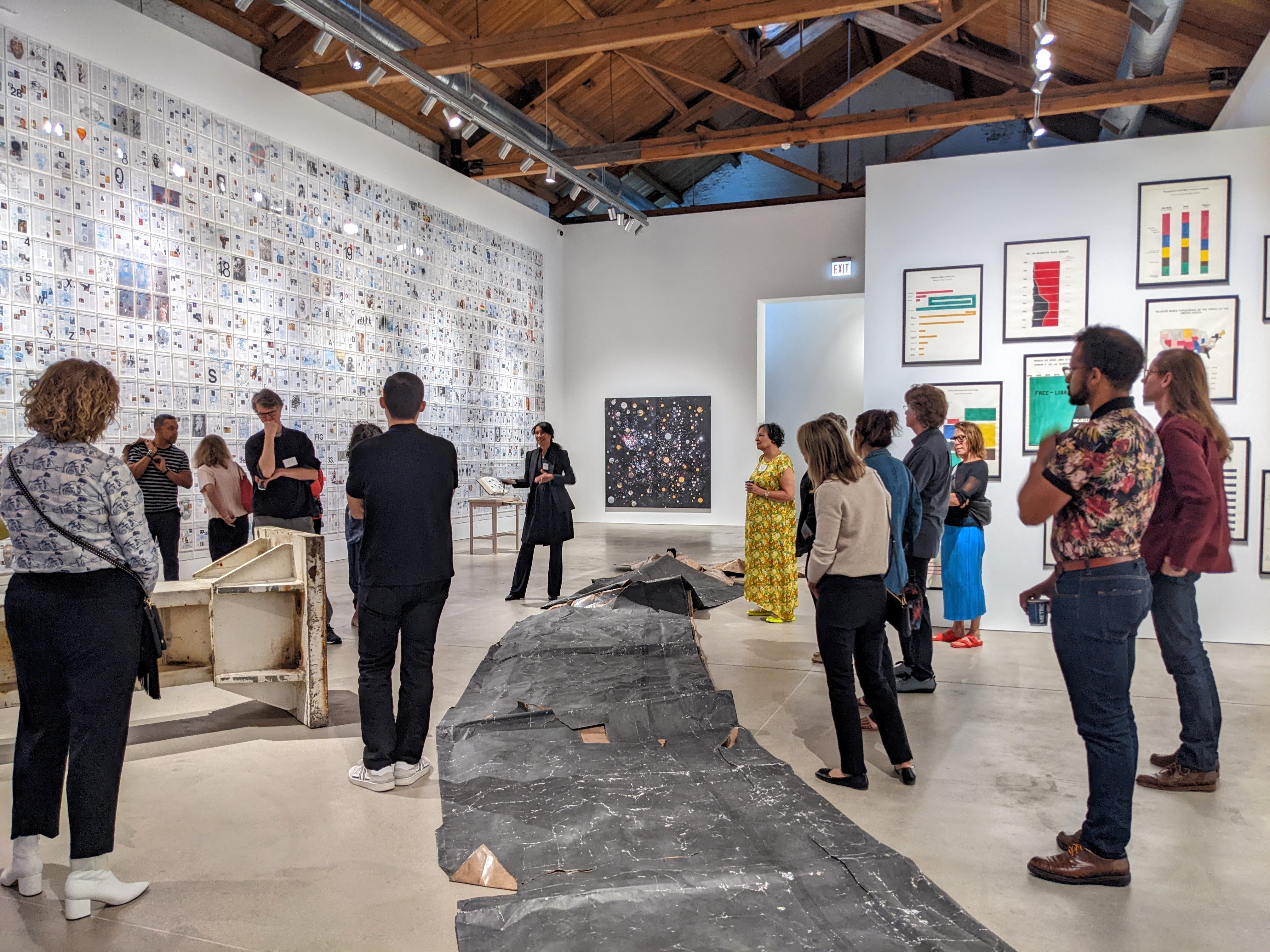 A group watches a speaker in an art gallery